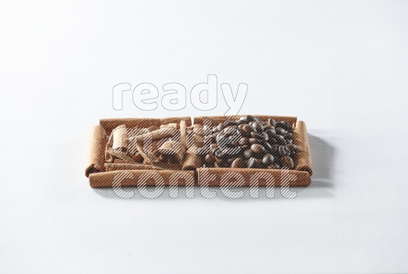 مربعان من أعواد القرفة ممتلئان بحبوب القهوة وقطع من القرفة علي خلفية بيضاء