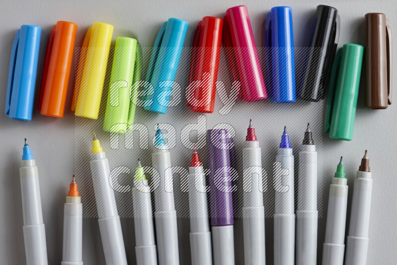 An arrangement of coloring pens in different colors on grey background