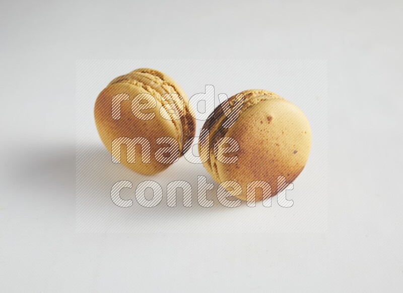 45º Shot of two Yellow Crème Brulée macarons on white background