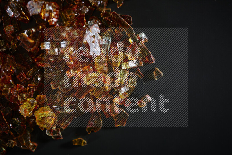 Transparent orange fragments of glass scattered on a black background