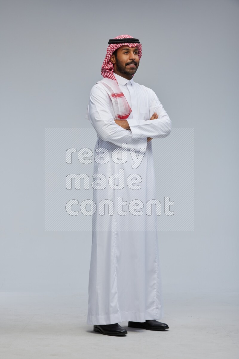Saudi man Wearing Thob and shomag standing with crossed arms on Gray background