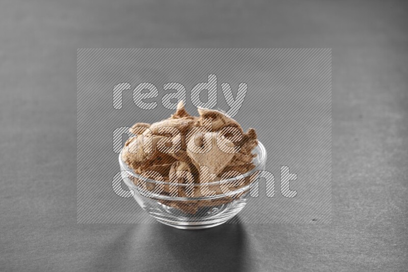 A glass bowl full of ginger on black flooring