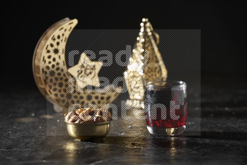 مكسرات في وعاء معدني مع مشروب الكركديه بجانب فوانيس ذهبية علي خلفية سوداء