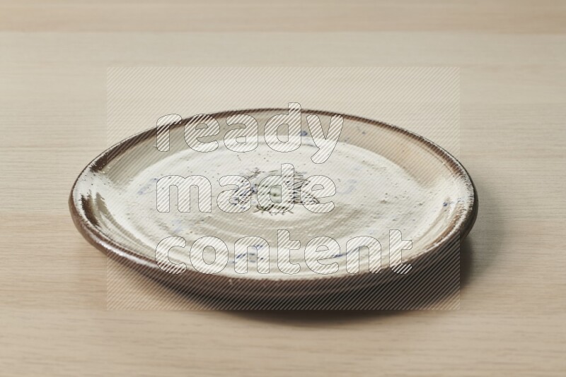 A decorative pottery plate on light wooden background