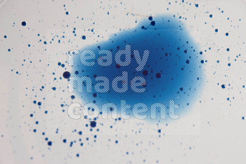 Close-ups of abstract blue watercolor drops on oil Surface on white background
