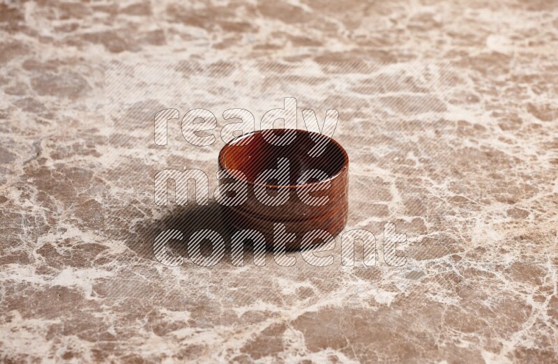 A brown pottery bowl on beige marble background