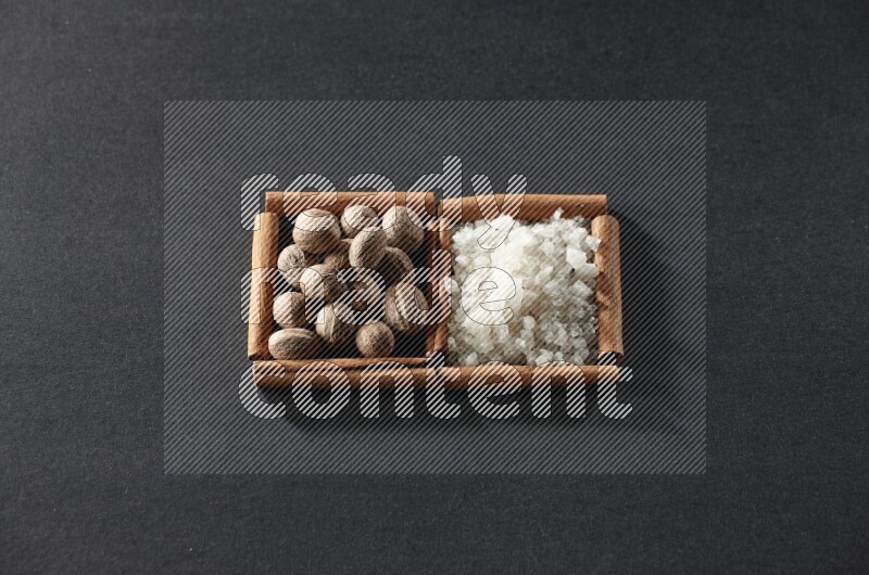 2 squares of cinnamon sticks full of nutmeg and white salt on black flooring