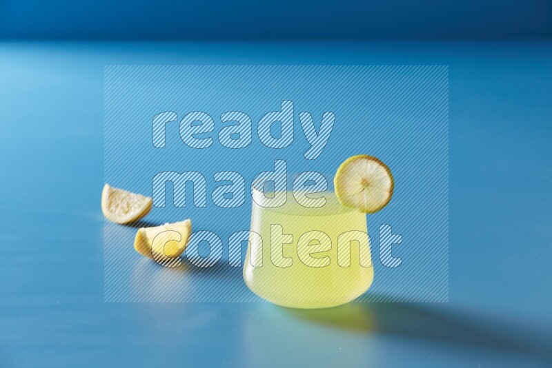 glass of lemon juice with lemon slice  on blue background