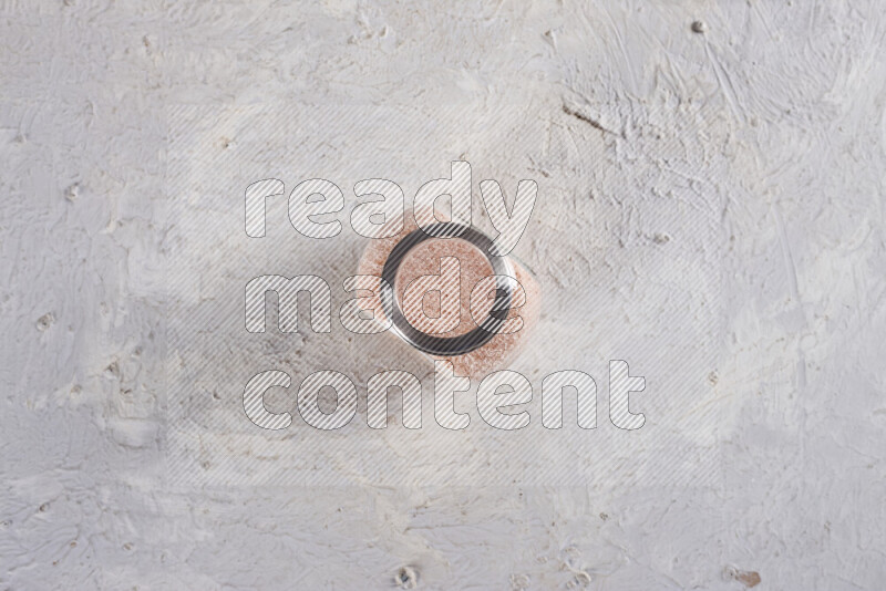 A glass jar full of fine himalayan salt on white background