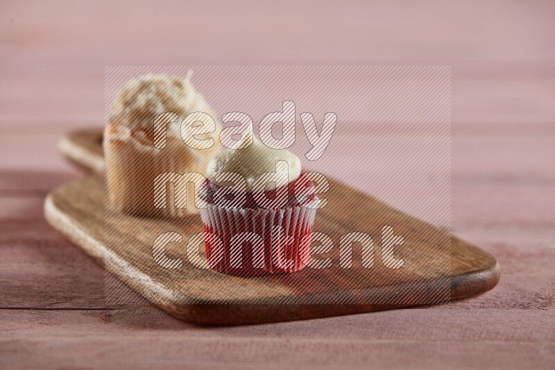 Red velvet mini cupcake topped with cream on a wooden board