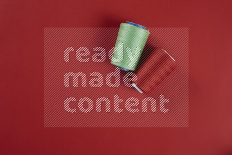 مجموعة من أدوات الخياطة والتفصيل خضراء وحمراء اللون على خلفية حمراء