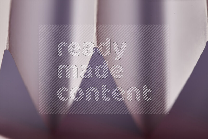 A close-up abstract image showing sharp geometric paper folds in white and pink gradients