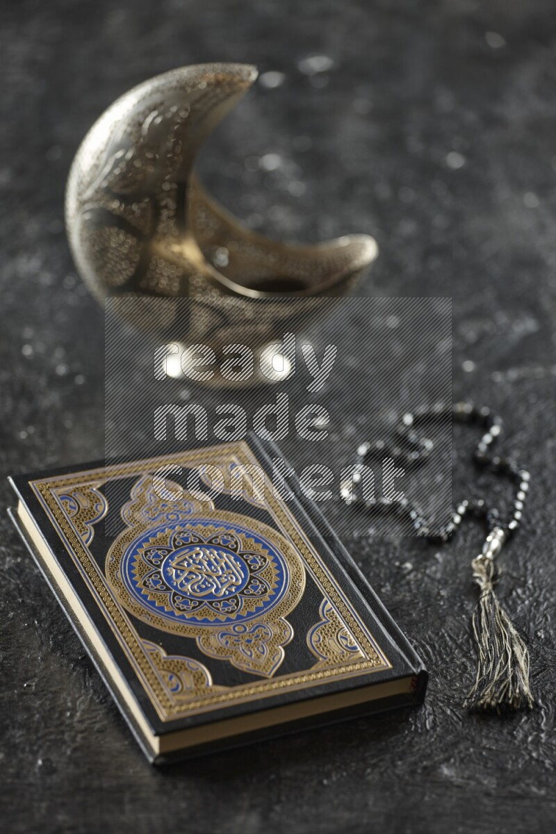 A silver lantern with different drinks, dates, nuts, prayer beads and quran on textured black background