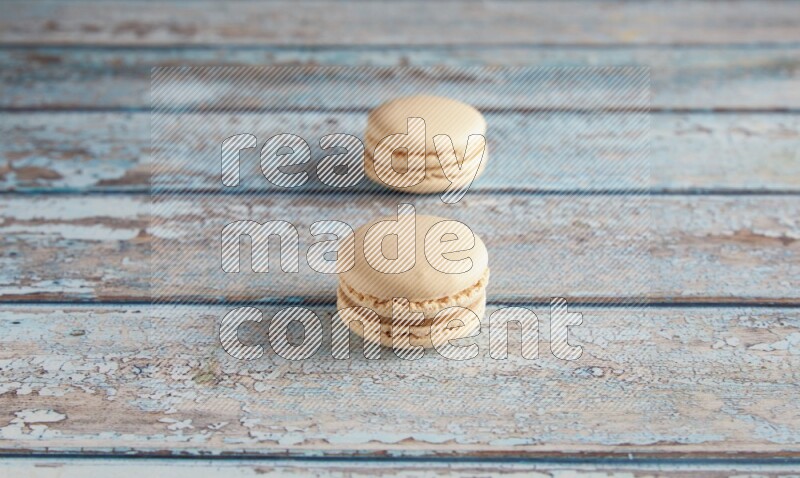45º Shot of two White Caramel fleur de sel macarons on a light blue wooden background