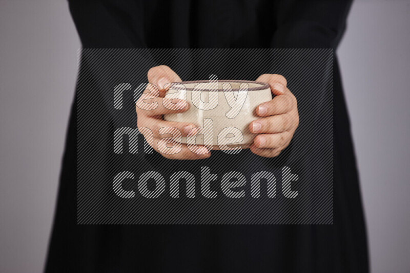 A woman in black abaya holding different pottery essentials in different positions