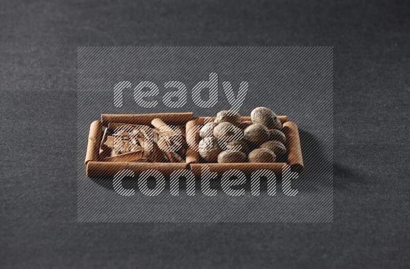 مربعان من أعواد القرفة ممتلئان بقطع من القرفة وجوزة الطيب علي خلفية سوداء