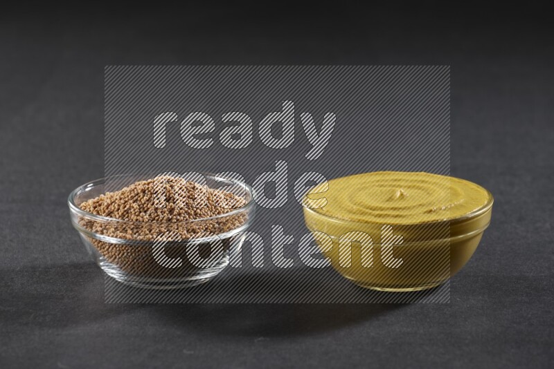 2 glass bowls, one full of mustard seeds and the other full of mustard paste on black flooring