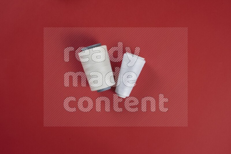 A white collection of sewing and tailoring tools arranged on a red background
