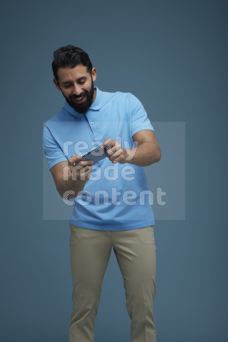 Man playing a game on his phone in a blue background wearing a Blue shirt