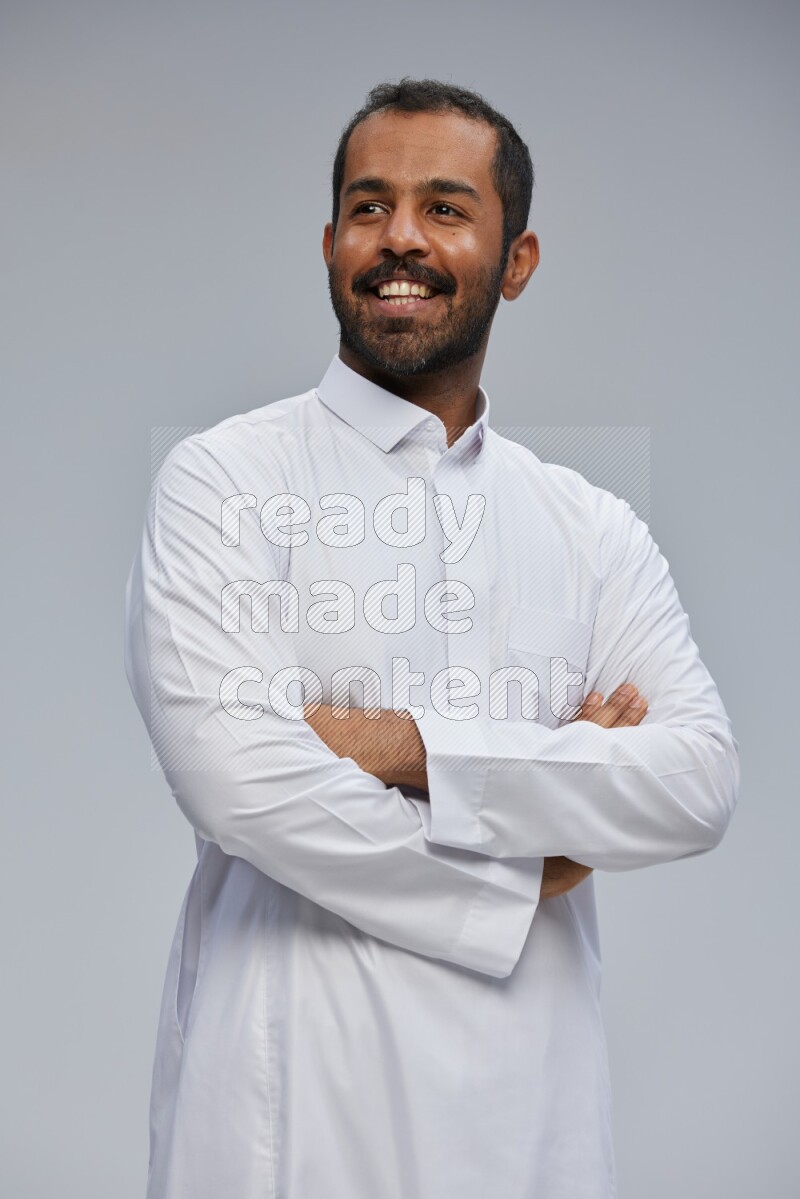 Saudi man wearing Thob standing with crossed arms on Gray background
