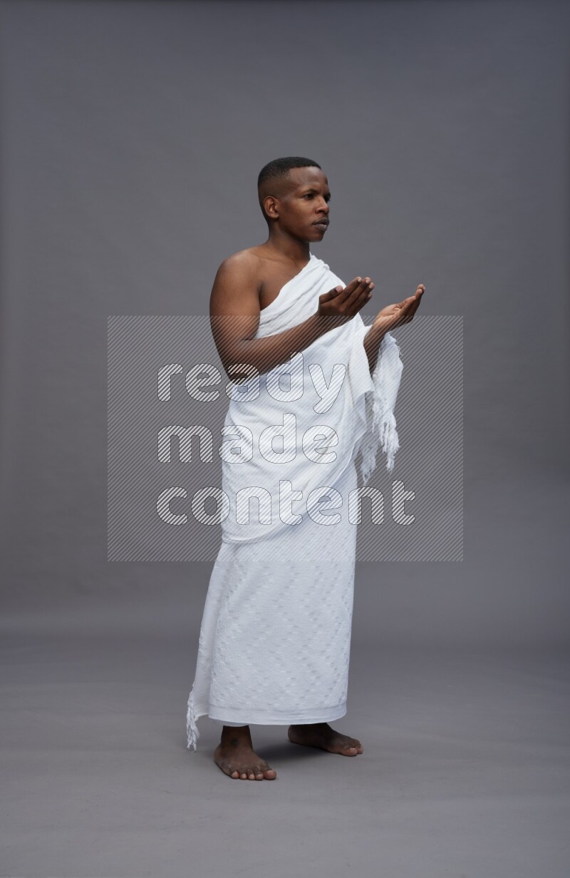 A man wearing Ehram Standing dua'a on gray background