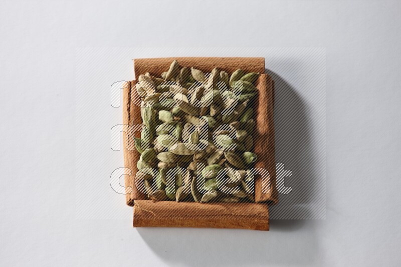 A single square of cinnamon sticks full of cardamom on white flooring
