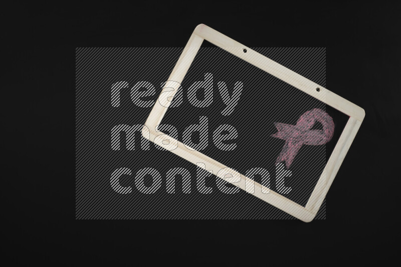 A drawing of pink ribbon on blackboard on black background