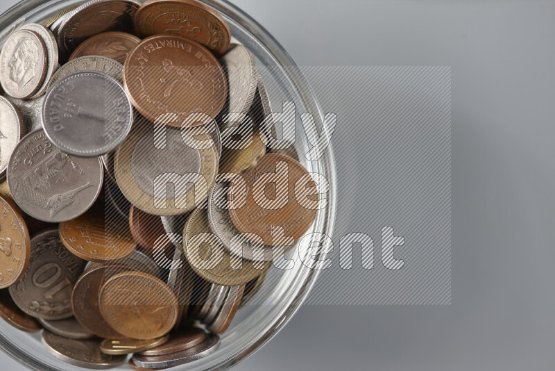 Random old coins in a glass bowl on grey background