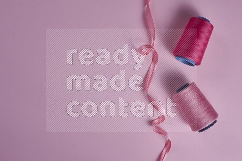 A pink collection of sewing and tailoring tools arranged on a pink background