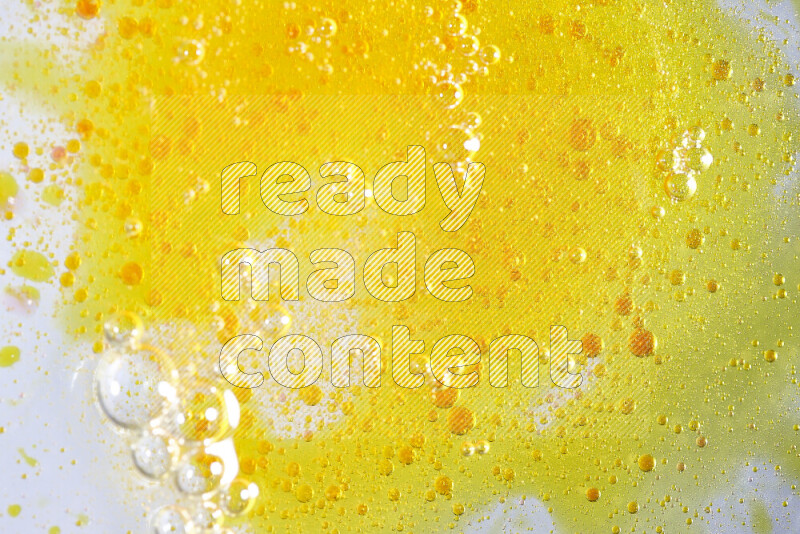 Close-ups of abstract yellow watercolor drops on oil Surface on white background