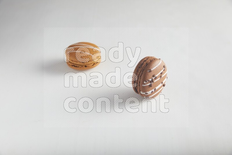 45º Shot of of two assorted Brown Irish Cream, and Brown white Chocolate Caramel macarons on white background