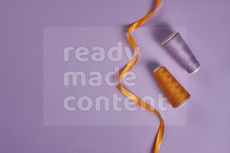 مجموعة من أدوات الخياطة والتفصيل برتقالية اللون على خلفية أرجوانية