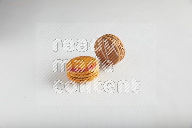 45º Shot of of two assorted Brown Irish Cream, and Orange Exotic macarons on white background