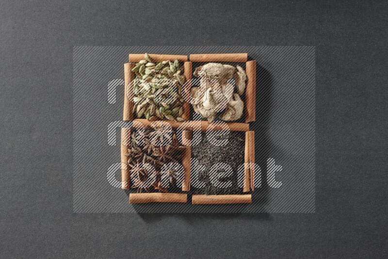4 squares of cinnamon sticks full of tea, star anise, dried ginger and cardamom on black flooring