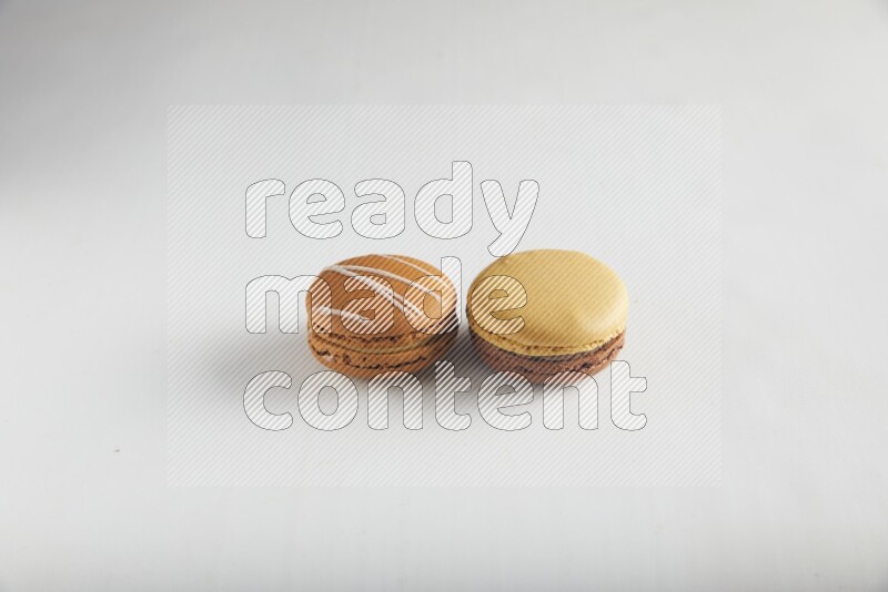 45º Shot of of two assorted Brown Irish Cream, and Yellow, and Brown Chai Latte macarons on white background