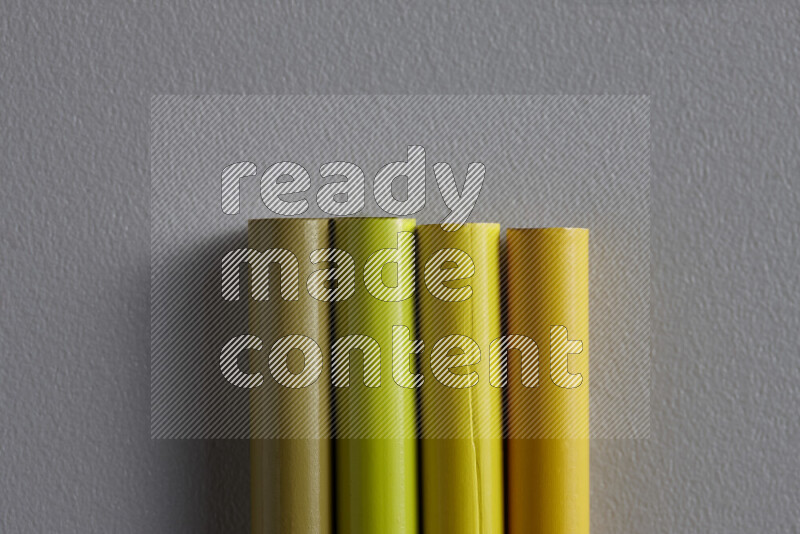 A collection of sharpened colored pencils arranged showcasing a gradient of yellow hues on grey background
