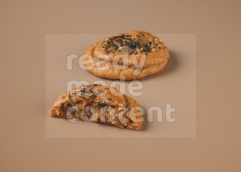 a Hasawi cookie field of date and herbs with another one cut in half on a brown background