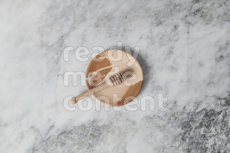 Multicolored pottery plate with wooden honey dipper in it on grey marble background