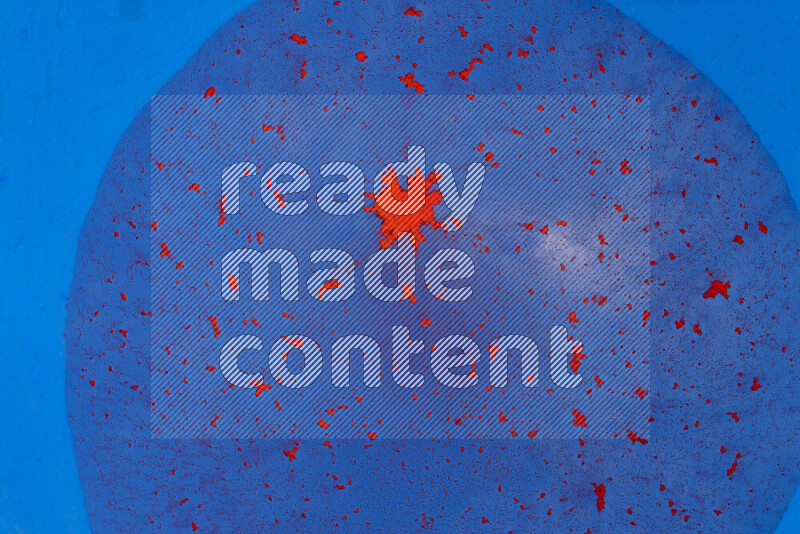 The image captures a dramatic splatter of red paint over a blue backdrop