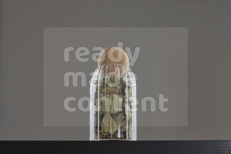 Bay laurel leaves in a glass jar on black background