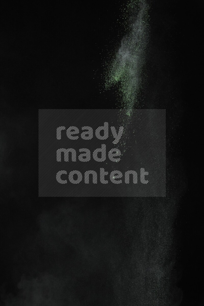 A side view of green powder explosion on black background