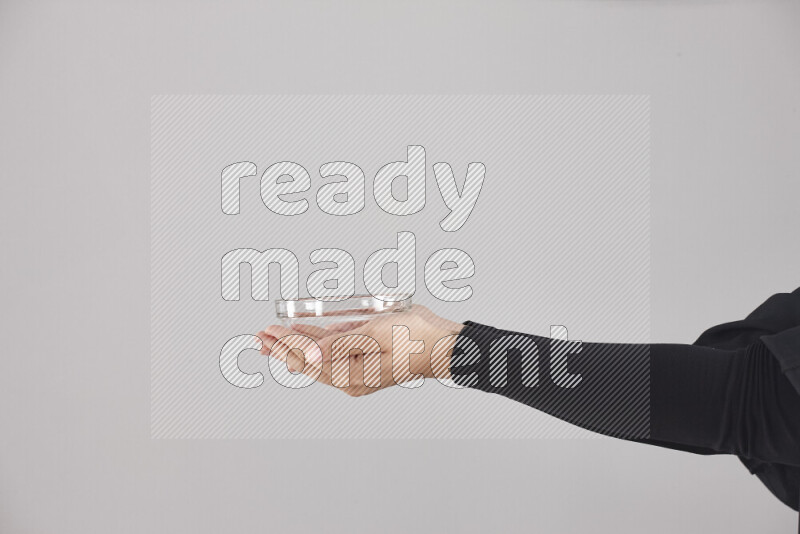 A woman in black abaya holding different glassware in different positions