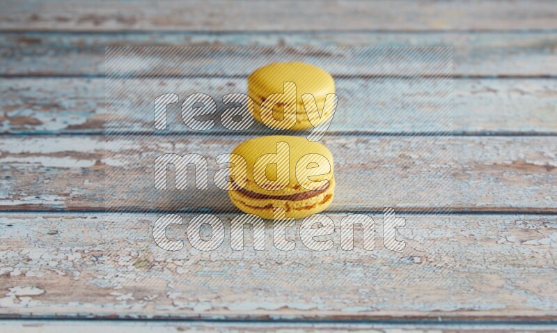 45º Shot of two Yellow Lemon macarons on light blue wooden background