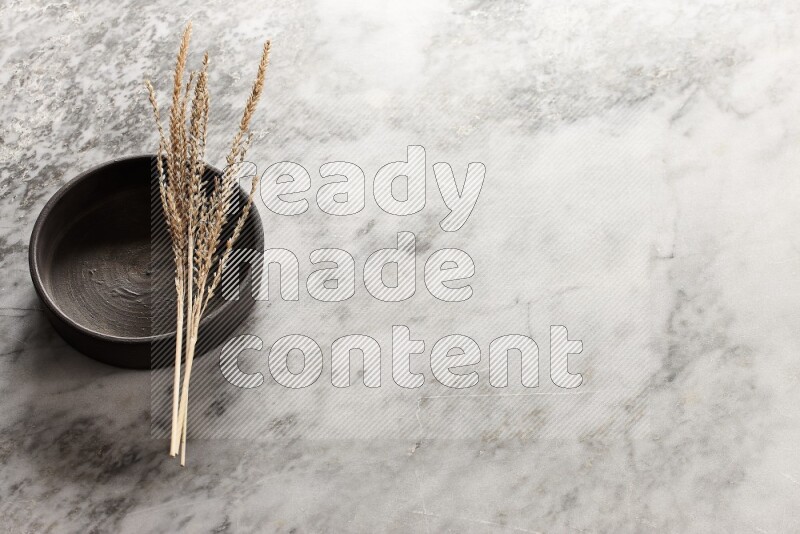 Wheat stalks on Black Pottery Oven Plate on grey marble flooring, 45 degree angel