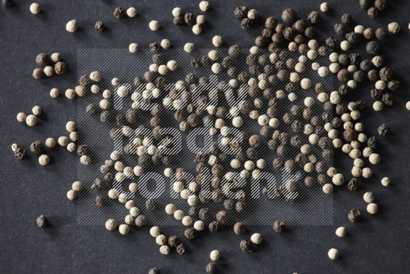 حبوب الفلفل المختلطة السوداء والبيضاء على أرضية سوداء