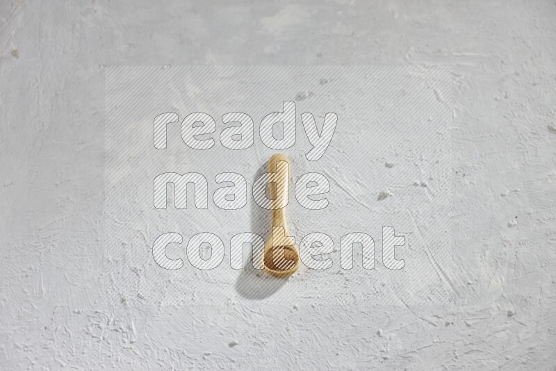 Cinnamon powder in a wooden spoon on a white background