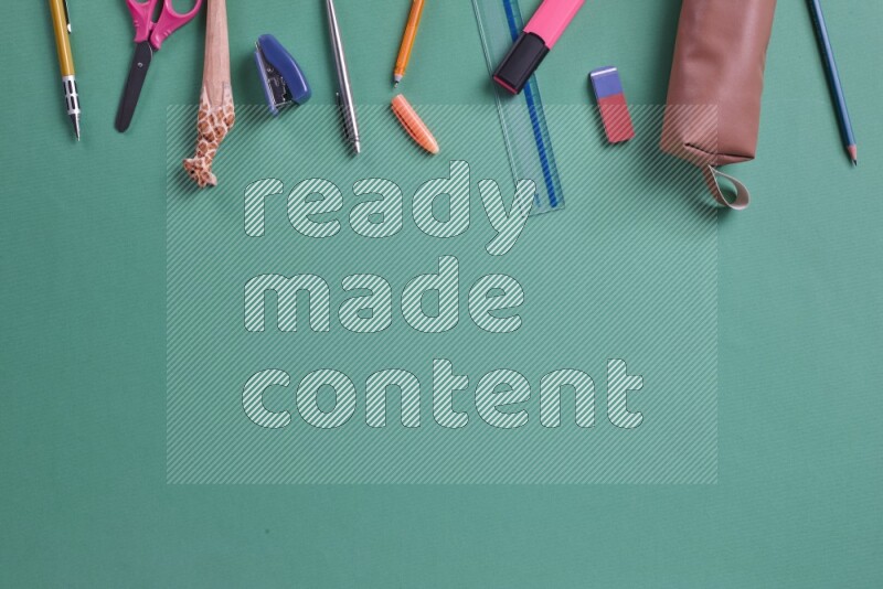 Different school supplies on green background