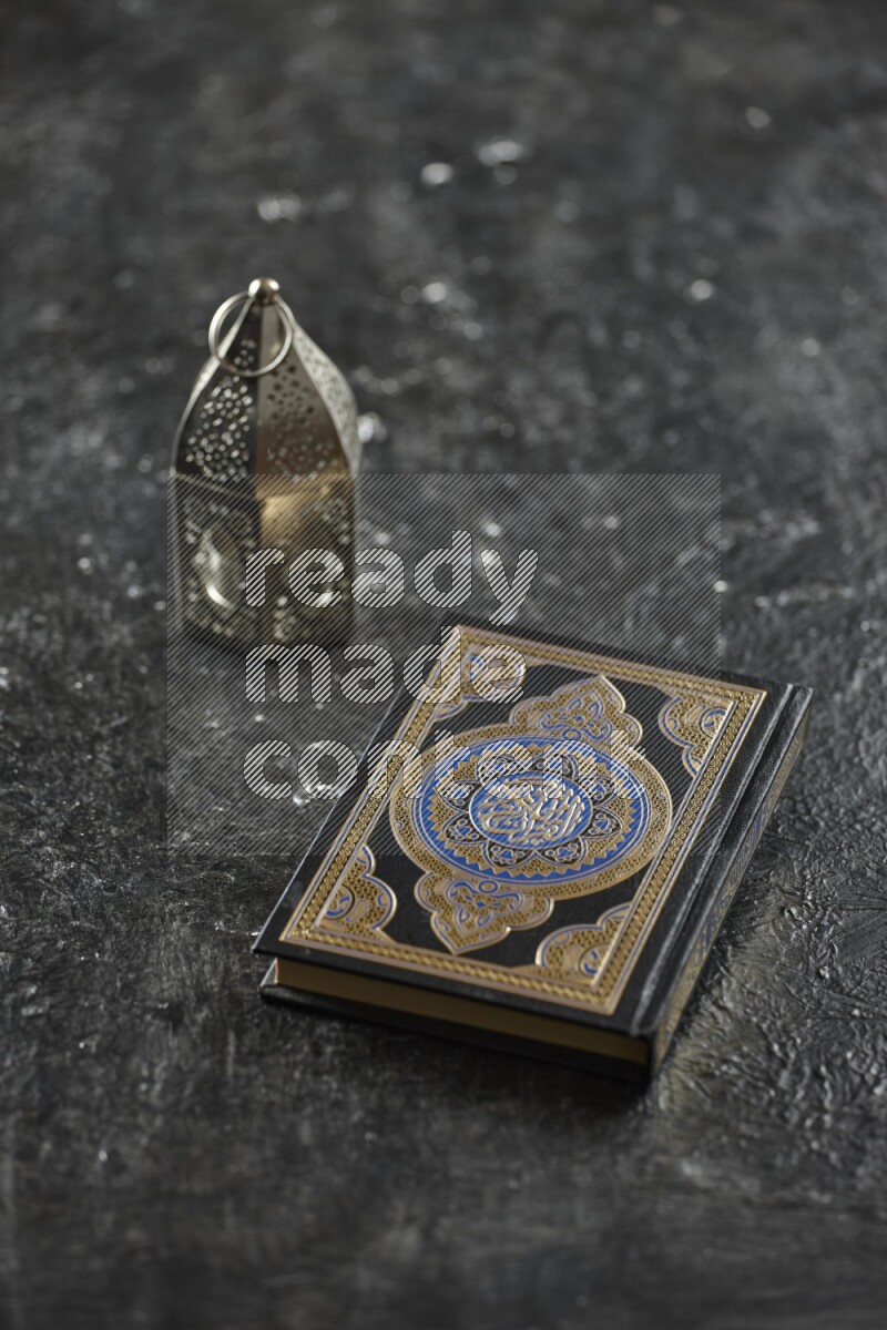 A silver lantern with different drinks, dates, nuts, prayer beads and quran on textured black background