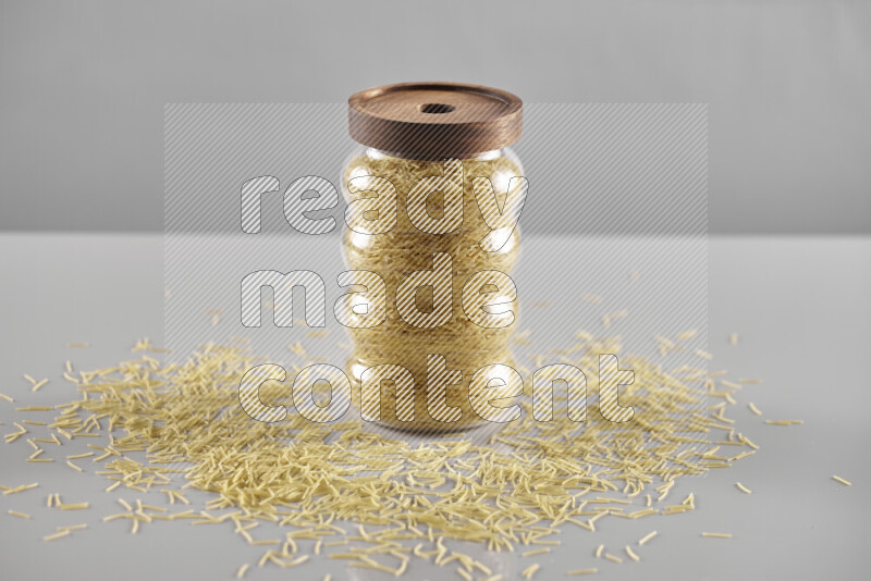 Raw pasta in a glass jar on light grey background