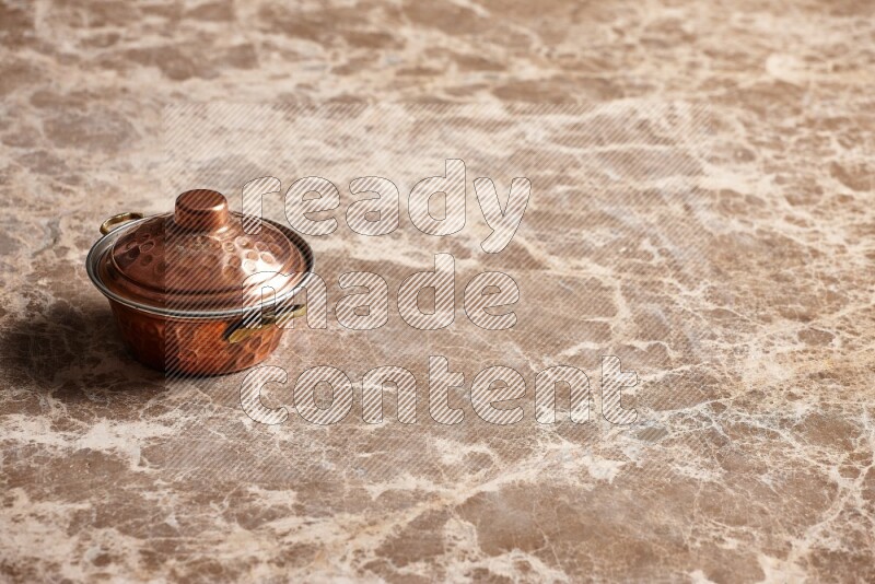 A small copper pot on beige marble background